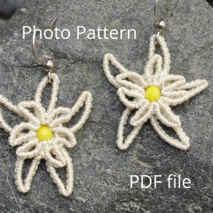 May include: A pair of white crocheted earrings shaped like edelweiss flowers with yellow bead centers. The earrings are hanging from silver hooks. The text "Photo Pattern" and "PDF file" are visible in the image.