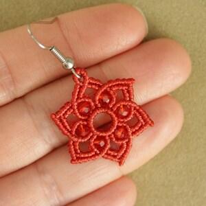 May include: Red crocheted earring with a star-shaped design and red glass beads.