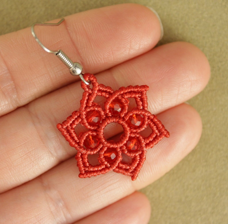 May include: Red crocheted earring with a star-shaped design and red glass beads.