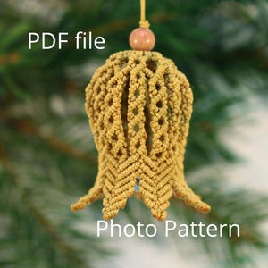 Peut inclure: Ornement en macramé jaune moutarde en forme de cloche, avec des motifs de nœuds complexes. Il comporte une petite perle en bois en haut et le texte "PDF file" et "Photo Pattern".