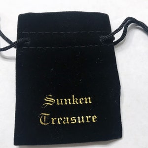 May include: A black velvet drawstring bag with gold lettering that reads "Sunken Treasure".