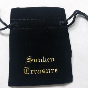 Puede incluir: Una bolsa de terciopelo negro con cord&oacute;n de ajuste y bordado dorado que dice "Sunken Treasure".