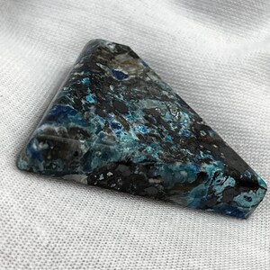 May include: A triangular piece of blue and black chrysocolla with a marbled pattern.