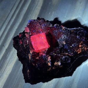 Op de afbeelding: Een donkerrode en zwarte steen met een helderrood kristal erin.