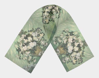 May include: A green silk scarf with a floral print of white roses in a vase. The scarf is folded in half and the ends are hanging down.
