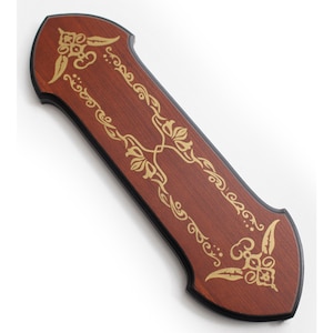 May include: A wooden sword display plaque with a dark brown finish and gold floral designs. The plaque has a pointed top and bottom.
