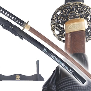 Op de afbeelding: Een zwart en bruin katana zwaard met een decoratief gouden en zwart handvat. Het zwaard staat op een zwarte standaard met het woord "Keizer" erop.