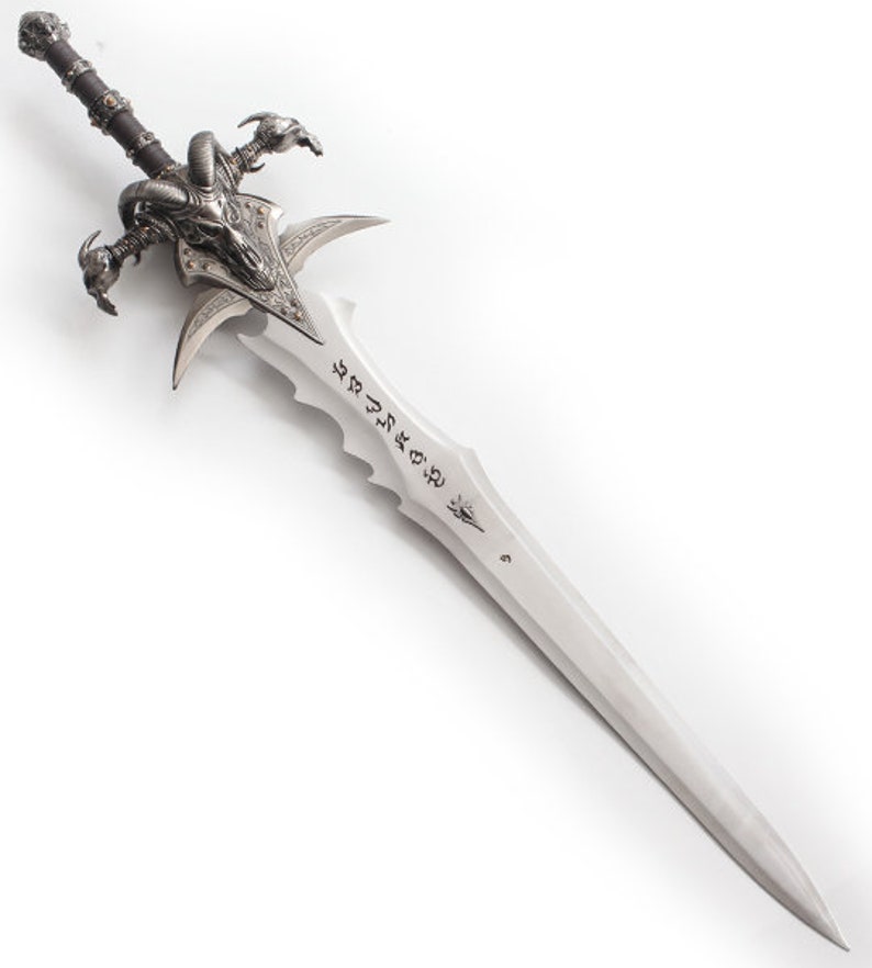 May include: A detailed fantasy sword with a silver blade and intricate hilt. The hilt features a skull design with horns and claw-like elements. The blade has etched inscriptions and a pointed tip, showcasing a medieval or fantasy theme.