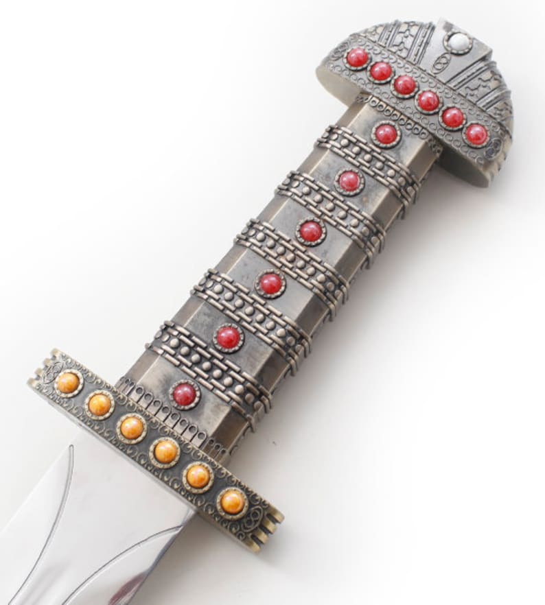 May include: A silver sword with a red and gold pommel. The pommel is decorated with a pattern of circles and squares. The sword has a silver blade and a silver handle.