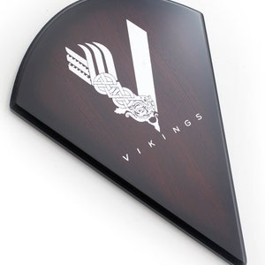May include: A dark brown wooden shield with a white Viking logo and the word "VIKINGS" in white lettering.