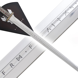 May include: A silver Viking sword with a black and red scabbard. The sword has runes engraved on the blade and the scabbard has a Viking shield design. The sword is displayed on a white background.