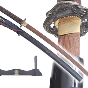 Może przedstawiać: Czarny i brązowy miecz katana z rękojeścią w kształcie smoka i pochwą z drewna. Miecz stoi na czarnym stojaku z złotym logo.