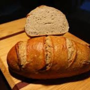 Könnte beinhalten: Ein frisch gebackenes Sauerteigbrot mit einer knusprigen Kruste und einem weichen, luftigen Inneren. Das Brot ist in der Mitte durchgeschnitten und zeigt die Krume.