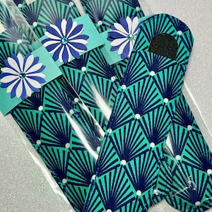 May include: Three teal blue nail files with a white and navy blue geometric pattern. Each file is wrapped in clear plastic and decorated with a white and blue flower with a sparkly center.