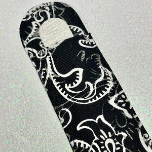 May include: Black and white paisley patterned fabric with a white circle cut out in the center.