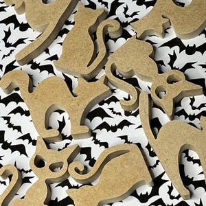 May include: A collection of unfinished wooden cat and bat shapes, perfect for crafting. The shapes are light brown and vary in size and pose. They are arranged on a black and white bat-patterned background, ideal for Halloween decorations.
