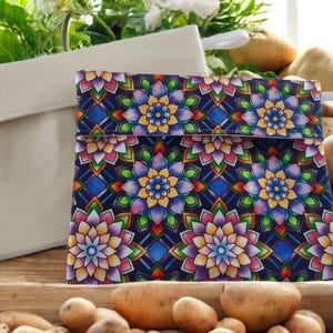 May include: Two reusable cloth bags, one white and one with a colorful floral pattern on a dark blue background. The bags are sitting on a wooden surface with potatoes in the foreground.