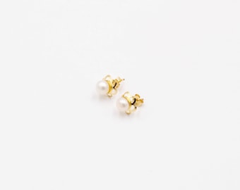 May include: A pair of gold pearl earrings with a delicate floral design.