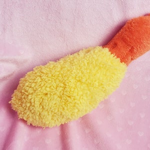 May include: A yellow and orange plush toy shaped like a shrimp. The toy is made of soft, fuzzy fabric and has a realistic shrimp shape.