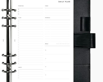 May include: A black leather bound daily planner with a silver ring binder. The planner has sections for priorities, to do, schedule, meals, and habits. The planner has a black leather flap with a silver clasp.