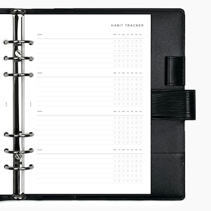 May include: A black leather bound planner with a white page open to a habit tracker. The tracker has a section for each week with a column for each day of the week. There are rows of circles for marking habits.
