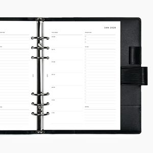 May include: Black leather planner open to a weekly spread for January 2026. The planner features a silver binder mechanism and a closure strap. The pages are white with black text and lines for scheduling and to-do lists.