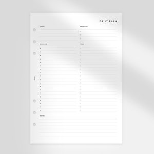 May include: A white daily planner with a black header that says "DAILY PLAN". The planner has sections for "TODAY", "SCHEDULE", "PRIORITIES", "TO DO", and "NOTES".