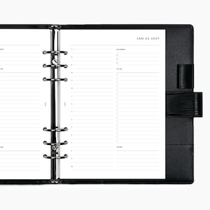 May include: A black leather ring binder planner featuring a six-ring metal mechanism. The open white page displays a daily schedule for Saturday, Jan 02 2027, with hourly time slots, a to-do list section with circular checkboxes, and a notes area.