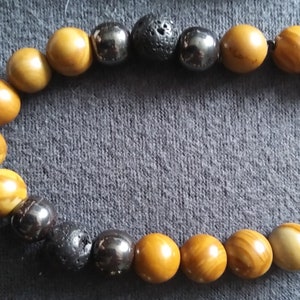 Könnte beinhalten: Ein Armband aus braunen und schwarzen Perlen. Das Armband besteht aus einer Mischung aus runden und ovalen Perlen. Die Perlen sind auf einer schwarzen Schnur aufgefädelt.