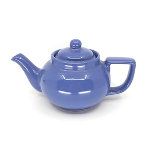 May include: A periwinkle blue ceramic teapot with a matching lid. The teapot has a curved spout, a square handle, and a small knob on the lid. The teapot is designed for brewing tea.