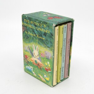 May include: A green slipcase box set titled The Bunny's Nutshell Library by Robert Kraus, featuring a rabbit illustration. It contains four small books with spines labeled The Silver Dandelion, Juniper, Springfellow's Parade, and The First Robin.