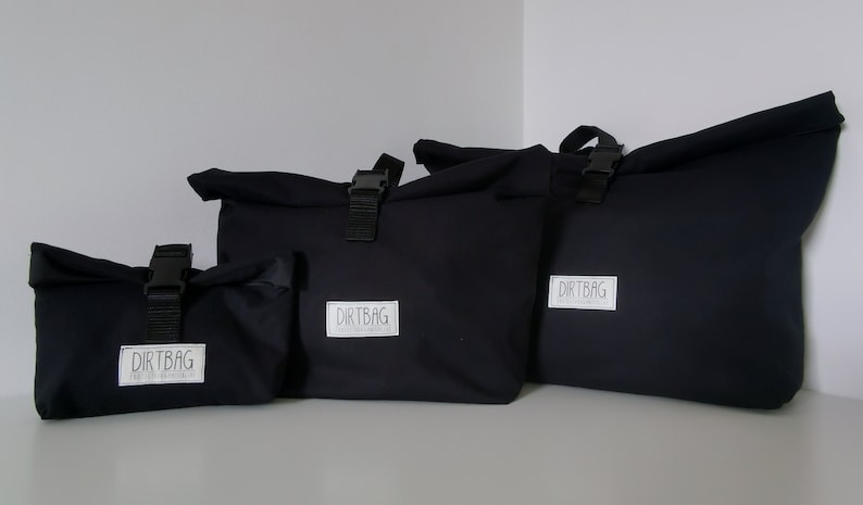 May include: Four black canvas bags with roll-top closures and adjustable straps. The bags have a white logo that reads "DIRTBAG" on the front.
