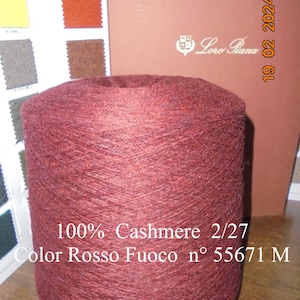 Puede incluir: Una bobina de hilo de cachemira 100% en un color rojo intenso. El hilo está etiquetado con "Color Rosso Fuoco n° 55671 M" y "100% Cashmere 2/27".
