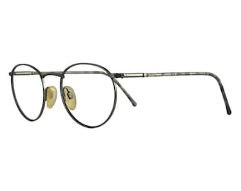 Op de afbeelding: Ronde bril met een donkergrijs metalen montuur en neuspads. De glazen zijn helder en de veren hebben een gemarmerd patroon. De bril heeft een klassieke, vintage uitstraling.
