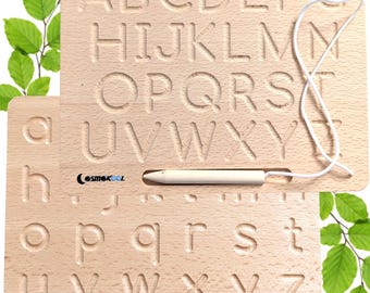 Puede incluir: Tablero de trazado de alfabeto de madera con un estilete y una cuerda. El tablero tiene dos lados, cada uno con el alfabeto en letras mayúsculas y minúsculas. Las letras están en relieve y se pueden trazar con el estilete.