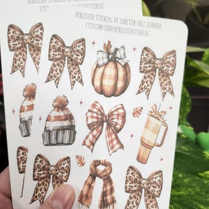 May include: Two sticker sheets featuring fall-themed illustrations. Designs include leopard print bows, a plaid pumpkin, a scarf, a beanie, and a coffee mug. The text "BEBLESSED STICKERS BY LORETTA-FALL LEOPARD" and Etsy shop URL are visible.