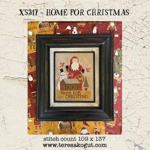 May include: A framed cross-stitch chart titled "HOME FOR CHRISTMAS" featuring a Santa Claus and snowman scene. The artwork is in a black frame, with a decorative border. The image includes the text "XS317 - HOME FOR CHRISTMAS".