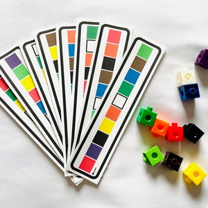 May include: A set of ten colour matching cards with a rainbow of colours, including red, orange, yellow, green, blue, indigo, and violet. The cards are arranged in a fan shape. There are also several colourful plastic blocks in the image.