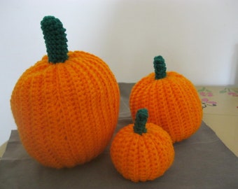 May include: Three crocheted pumpkins in various sizes. The largest pumpkin is orange with a green stem. The medium pumpkin is orange with a green stem. The smallest pumpkin is orange with a green stem.
