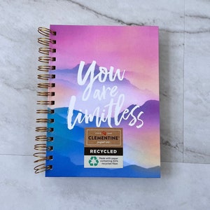 May include: A pink and blue spiral bound notebook with the words "You are limitless" on the front cover. The notebook is made with paper containing 60% recycled fiber.
