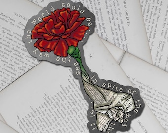 May include: A die-cut sticker featuring a vibrant red carnation flower with green leaves at the top, transitioning into a stem and base made of black and white newspaper print. The text "the world could be the way see in spite of that it is" is printed in white along the dark gray border.