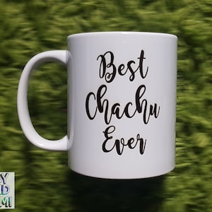 以下が含まれることがあります： 「Best Chachu Ever」の文字が黒い筆記体で書かれた白いセラミックマグ。マグカップにはカーブしたハンドルがあり、緑色の背景に置かれています。「Ray and Sami」のロゴが下部に表示されています。