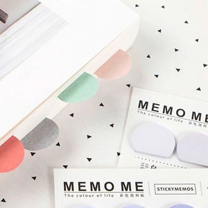 May include: A set of colourful sticky notes with rounded edges. The notes are in various colours, including pink, green, grey, and light blue. The notes are labelled "Memo Me" and "The colour of life".