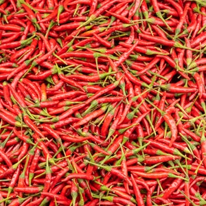 May include: A close-up, overhead shot of a pile of bright red chili peppers with green stems. The peppers are densely packed together, creating a vibrant and textured surface. The image highlights the fresh produce.