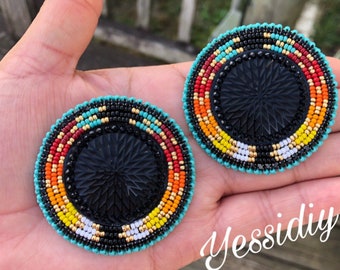 May include: A pair of round beaded earrings with a black center and a colorful design of turquoise, red, orange, yellow, white, and gold beads.