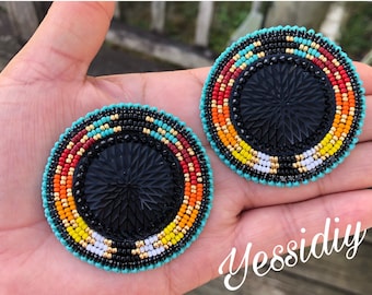 May include: A pair of round beaded earrings with a black center and a colorful beaded border. The border features turquoise, red, orange, yellow, white, and black beads.