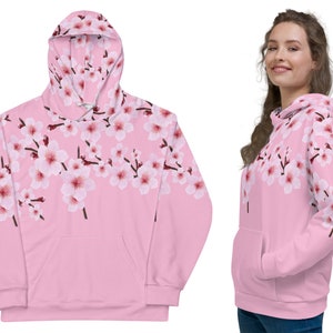 May include: Pink hoodie with a floral print of cherry blossoms. The hoodie has a drawstring hood and a kangaroo pocket.