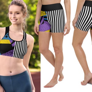 May include: A black sports bra and matching shorts set. The bra and shorts feature a patchwork design with black, white, yellow, purple, and blue elements. The shorts have a black waistband and vertical white stripes.