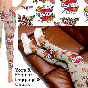 May include: Beige leggings featuring a repeating tattoo-style print of red hearts with blue banners reading LOVE, yellow roses, and arrows. The pattern includes green leaves and black tribal accents. The leggings are shown on a standing figure and a seated figure.