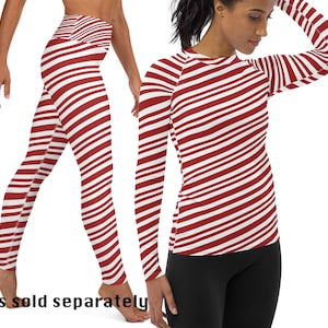 Puede incluir: Leggings y camiseta de manga larga de rayas rojas y blancas. La camiseta tiene un patrón de rayas diagonales. Las leggings tienen un patrón de rayas horizontales.